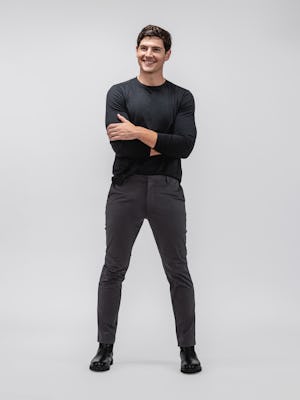model wearing black composite merino long sleeve tee and charcoal heather kinetic tapered pant facing forward with sleeves pulled up and arms crossed