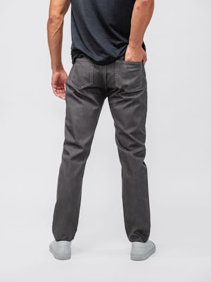 model wearing dark grey chroma denim and black composite merino zip polo facing away with hand in back pocket