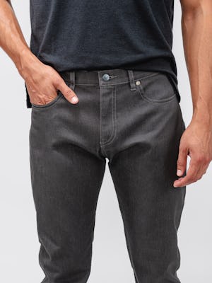 model wearing dark grey chroma denim and black composite merino zip polo facing forward zoomed in on hand in pocket