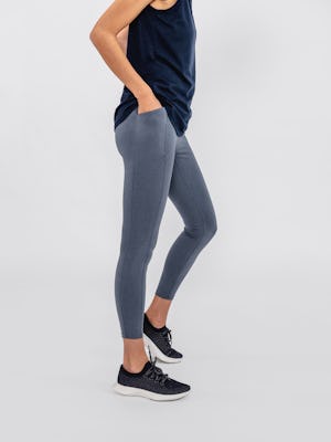 close up of model wearing indigo heather joule active legging and navy composite merino active tank facing to the side with hands in pockets