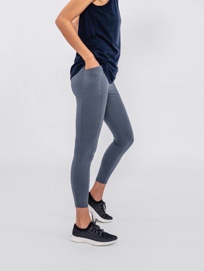 close up of model wearing indigo heather joule active legging and navy composite merino active tank facing to the side with hands in pockets