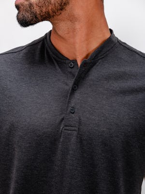 model wearing men's dark charcoal heather composite merino short sleeve henley close up of shirt with top button unbuttoned