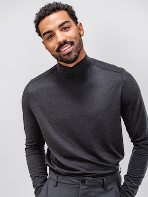 model wearing men's dark charcoal heather composite merino mock neck and grey heather velocity flannel pant facing forward with hands in pockets and shirt tucked in