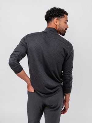 model wearing men's dark charcoal heather composite merino mock neck and grey heather velocity flannel pant facing away with hand in back pocket