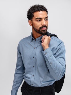 close up of model wearing chambray stripe hybrid button down and dark navy velocity dress pant facing forward with velocity blazer draped over shoulder