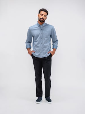 model wearing chambray stripe hybrid button down untucked and dark navy velocity dress pant facing forward with sleeves rolled and hands in pockets