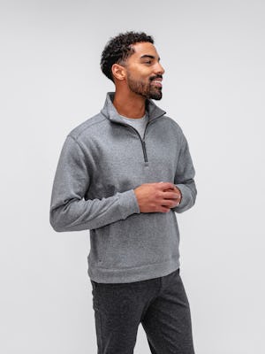 model wearing men's classic grey heather hybrid 1/4 zip pullover and charcoal heather fusion pant facing to the side with hands clasped