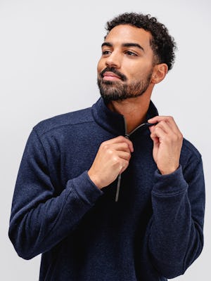 model wearing men's indigo heather hybrid 1/4 zip pullover facing forward zipping up pullover