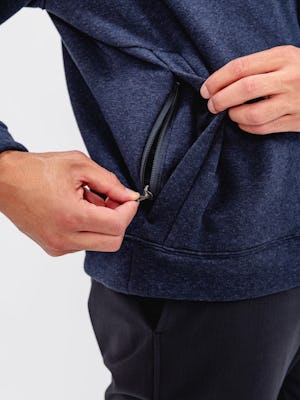 model wearing men's indigo heather hybrid 1/4 zip pullover close up of hidden zippered pocket