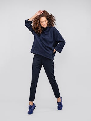 model women's indigo heather hybrid mock neck sweater and navy herringbone fusion straight leg pant facing forward with hand in pockets and other hand above head