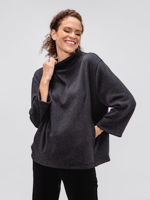 model wearing women's black tweed hybrid mock neck sweater and black kinetic pull on pant facing forward with hand on collar and other hand in pocket