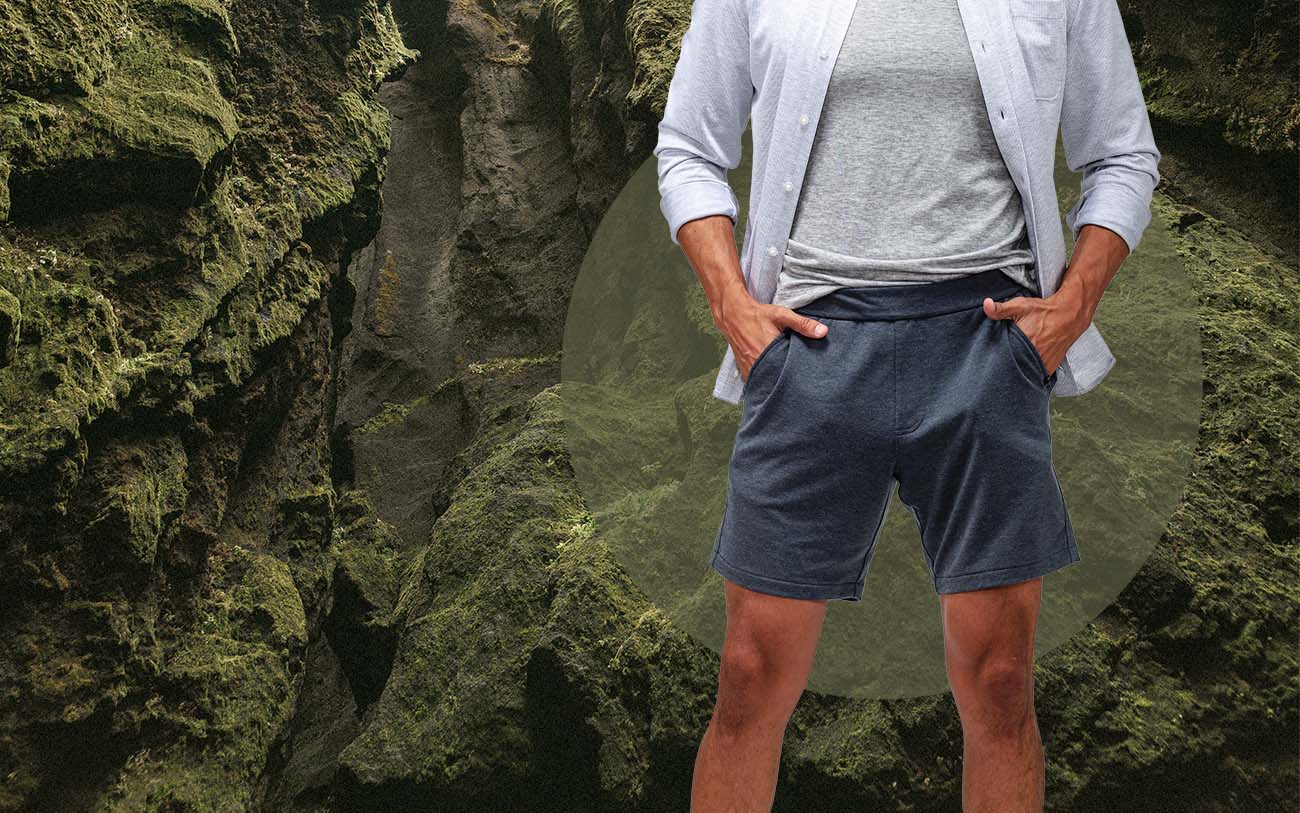 model wearing men's fusion terry shorts standing in front of a mossy background