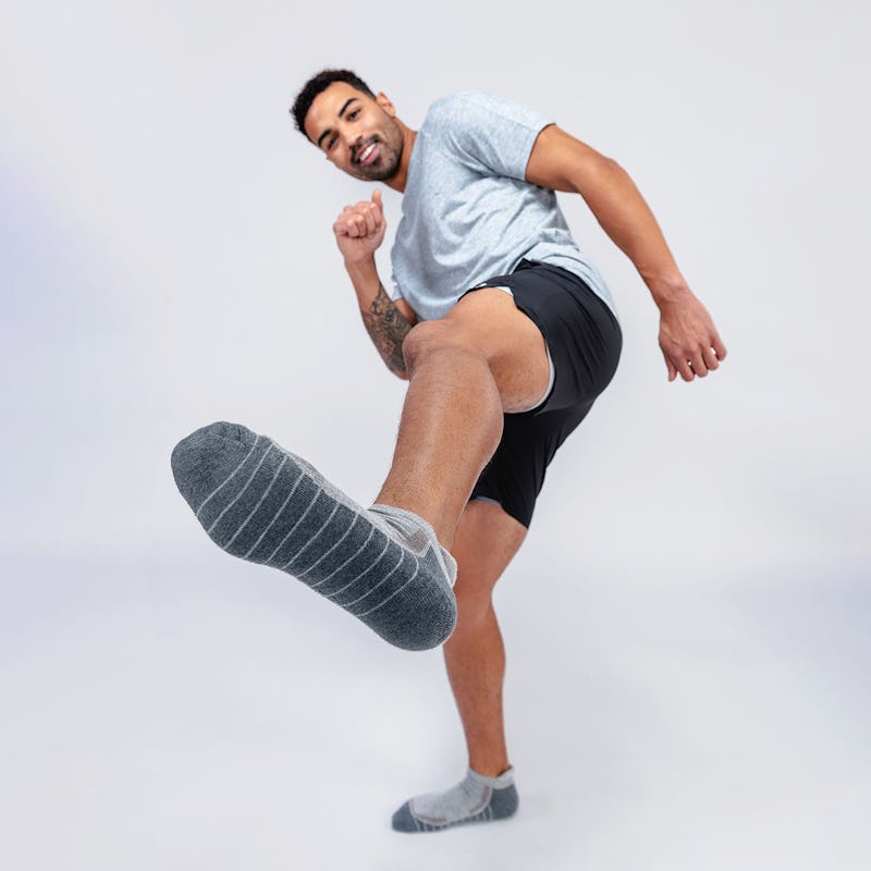 model wearing atlas ankle socks, newton active shorts and composite merino active tee kicking toward the camera