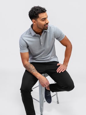 Men's Black Kinetic Jogger and Grey White Heather Apollo Polo on model sitting on chair
