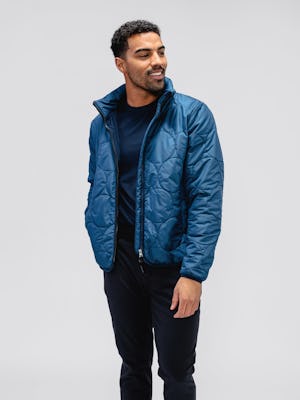 model wearing men's storm blue aurora jacket and navy pace tapered chino and navy composite merino tee facing forward with jacket unzipped and hand in pocket