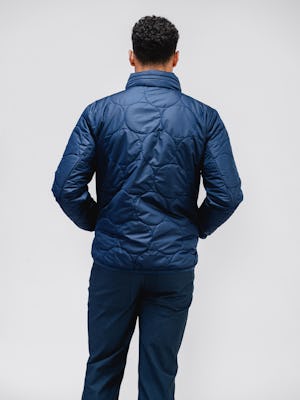 model wearing navy aurora jacket and kinetic twill 5-pocket pant facing away with hands in pockets