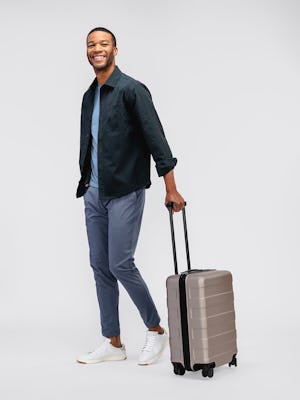 model wearing mens pace poplin overshirt navy and mens kinetic jogger slate blue with suitcase