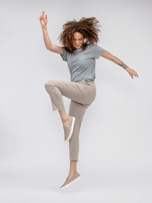 model jumping while wearing swift drape pants taupe and composite merino boxy tee pale grey heather  