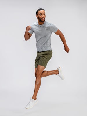 model wearing mens composite merino tee pale grey heather and mens pace poplin shorts olive running jump shot looking sideways