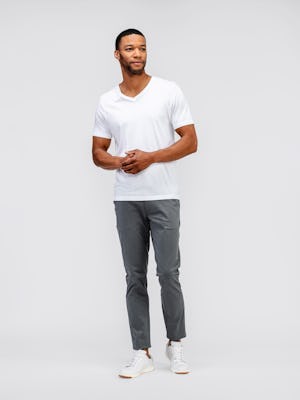 model wearing mens kinetic tapered pant slate grey and mens atlas v neck tee white standing full body looking sideways both hands together