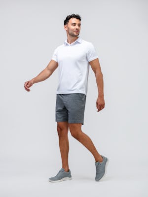 model walking forward wearing men's griffin grey rockport r+m lace up shoes and white apollo polo and grey heather fusion terry shorts