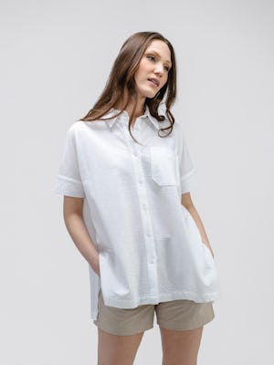 model wearing women's white hybrid seersucker short sleeve shirt and buff pace poplin short facing forward with hands in pockets