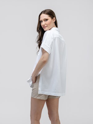 model wearing women's white hybrid seersucker short sleeve shirt and buff pace poplin short facing away with hands in pockets