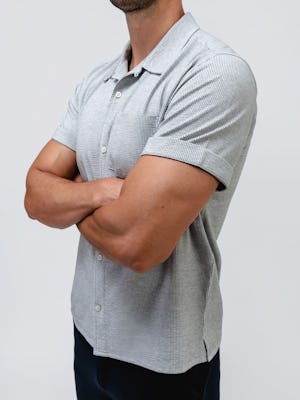 model wearing Men's Grey Tonal Stripe Hybrid Seersucker Short Sleeve Shirt and slate grey kinetic jogger zoomed in shirt details hands crossed
