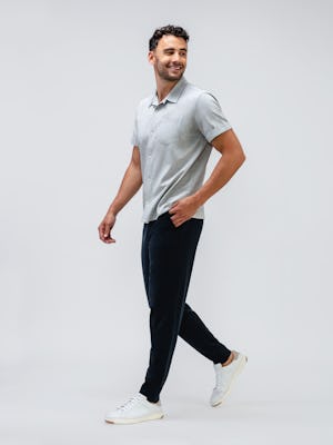 model wearing men's black fusion terry jogger and hybrid seersucker short sleeve shirt walking to the side with hand in pocket