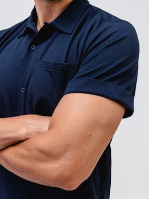 model wearing Men's Navy Hybrid Seersucker Short Sleeve Shirt zoomed in shirt details hands crossed