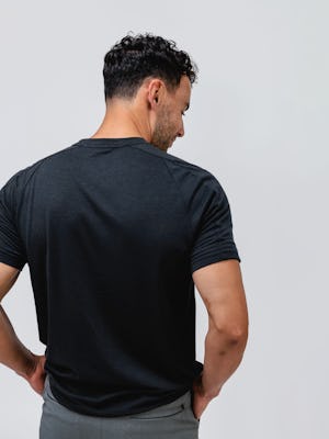 model wearing black composite merino active tee and slate grey kinetic pull on short facing away with hands in pockets