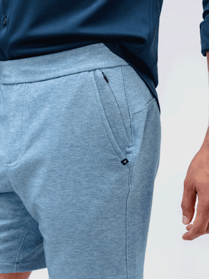 model wearing men's lunar blue fusion terry short and navy apollo raglan sport shirt close up of zip pockets