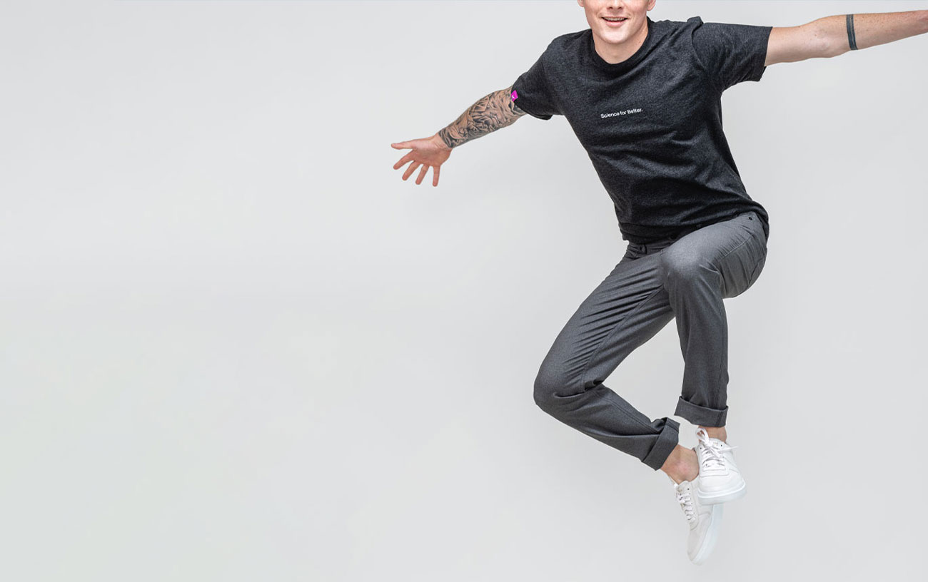 model wearing kinetic twill 5 pocket pant and science for better tee doing a big jump