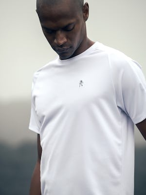 model wearing mens apollo x active tee white limited edition looking down at logo zoom shot europe photoshoot