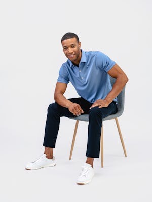 model wearing mens apollo polo steel blue and mens kinetic jogger navy sitting on chair