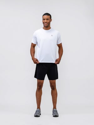 model wearing mens apollo x active tee white and mens newton active short black front full body holding end of tshirt