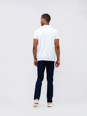 model wearing mens kinetic twill 5 pocket pant navy heather and mens high crew atlas tee white full body back both hands on side