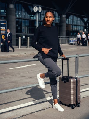 model wearing womens fusion double knit tunic black looking sideways at airport lifestyle with suitcase carry on one hand in pocket