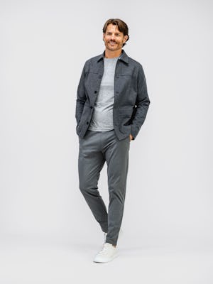 model wearing mens chore coat charcoal heather and mens composite merino long sleeve tee pale grey heather and mens fusion jogger slate grey full body front both hands in pocket