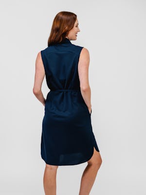 model wearing apollo sleeveless dress navy knee up both hands in pocket back body front