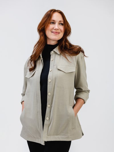model wearing womens fusion overshirt taupe womens composite merino mock neck black and womens fusion straight leg pant black waist up shot both hands in pocket