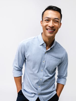model wearing mens hybrid button down shirt light blue stripe waist up both hands in pocket