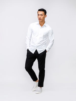 model wearing mens aero zero dress shirt white and mens kinetic jogger black both hands in pocket