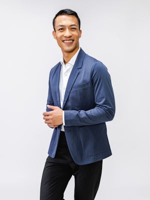 model wearing mens kinetic blazer shadow blue heather and mens velocity dress pant black both hands together