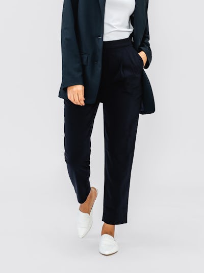 Navy Swift Drape Pant on woman walking forward with hand in pocket