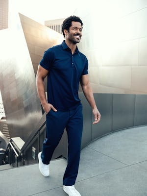 Men's Navy Apollo Polo and Azurite Velocity Dress Pant on model walking forward with hand in pocket