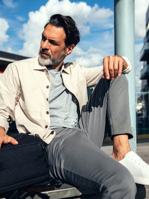 Pace Poplin Overshirt in buff and kinetic jogger slate grey on model sitting on bench with knee up