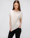 model wearing womens composite merino boxy tee taupe and womens kinetic pintuck pant black stretching her top