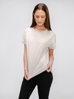 model wearing womens composite merino boxy tee taupe and womens kinetic pintuck pant black stretching her top