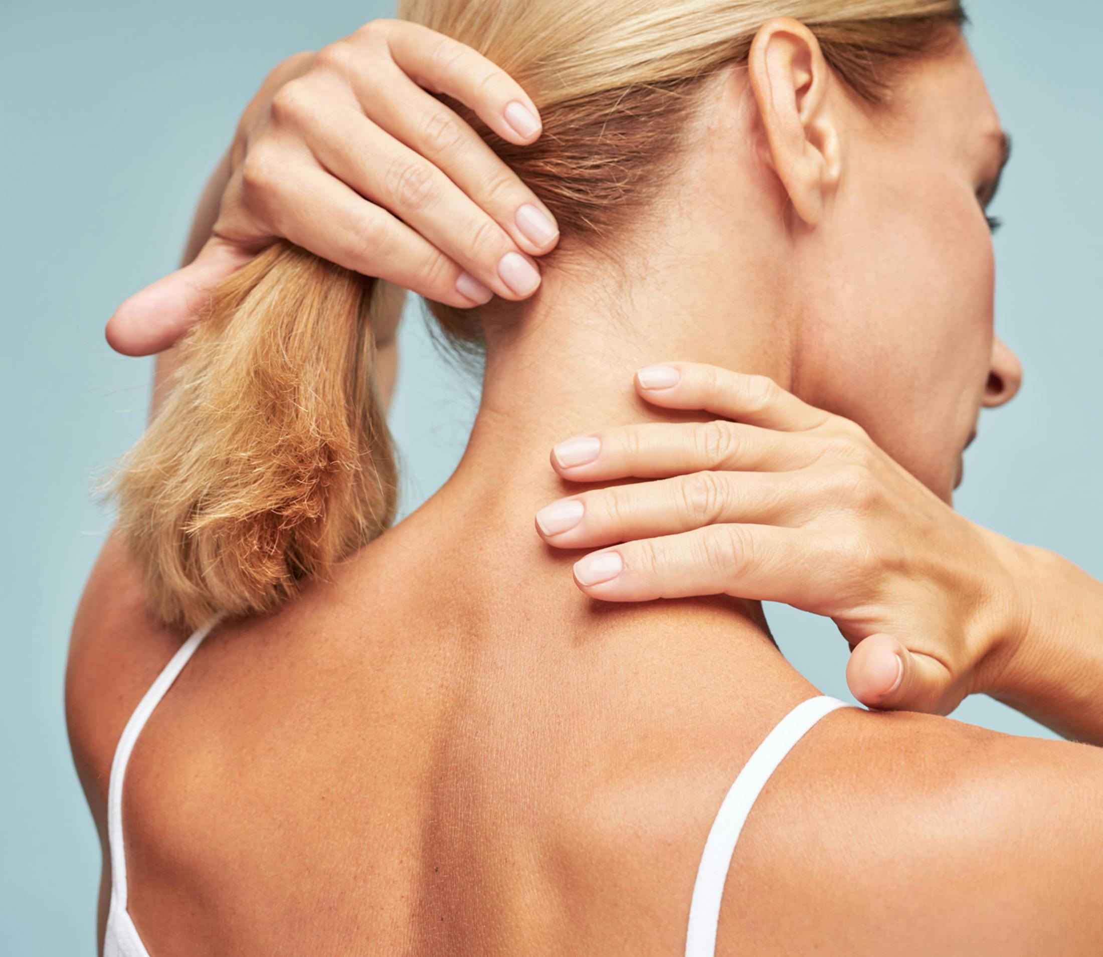 woman brushing her hair from her neck while touching her neck